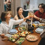 A lively gathering of friends sharing a meal, raising wine glasses in a cheerful indoor setting.
