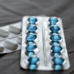 Detailed view of medication in blister packs showcasing blue softgel capsules and white pills.