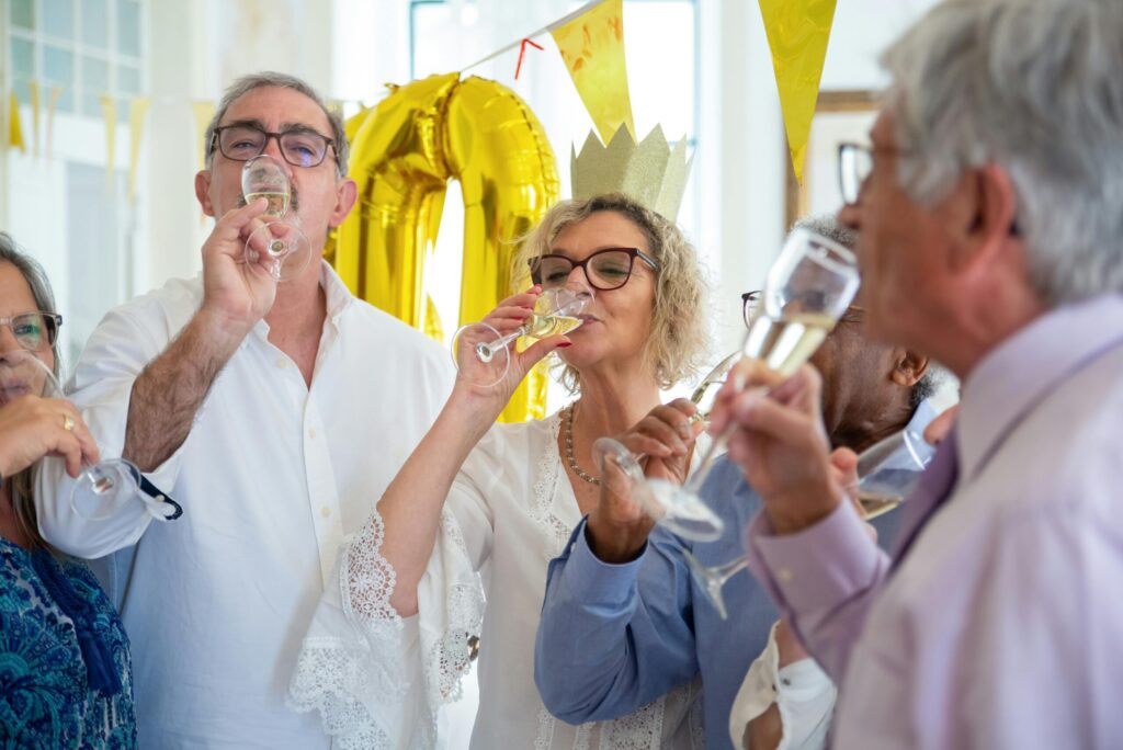 A joyful group of seniors celebrating a birthday indoors with champagne and smiles.