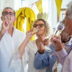 A joyful group of seniors celebrating a birthday indoors with champagne and smiles.