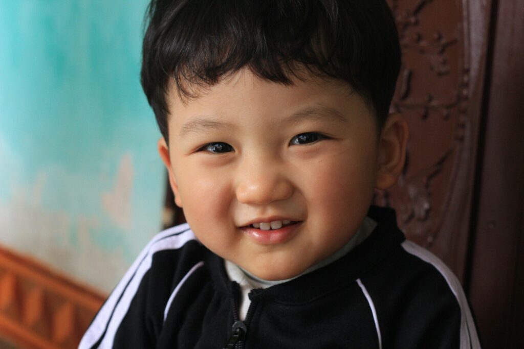 Cute child smiling warmly at the camera indoors with vibrant background.